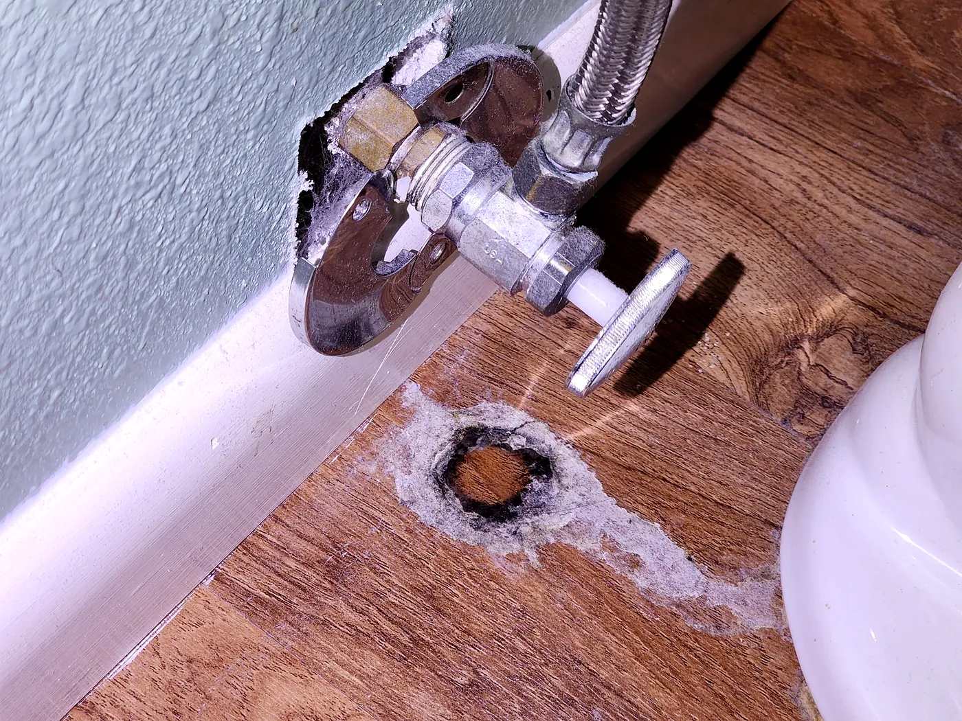 Corroded shut-off valve leaking onto a laminate floor