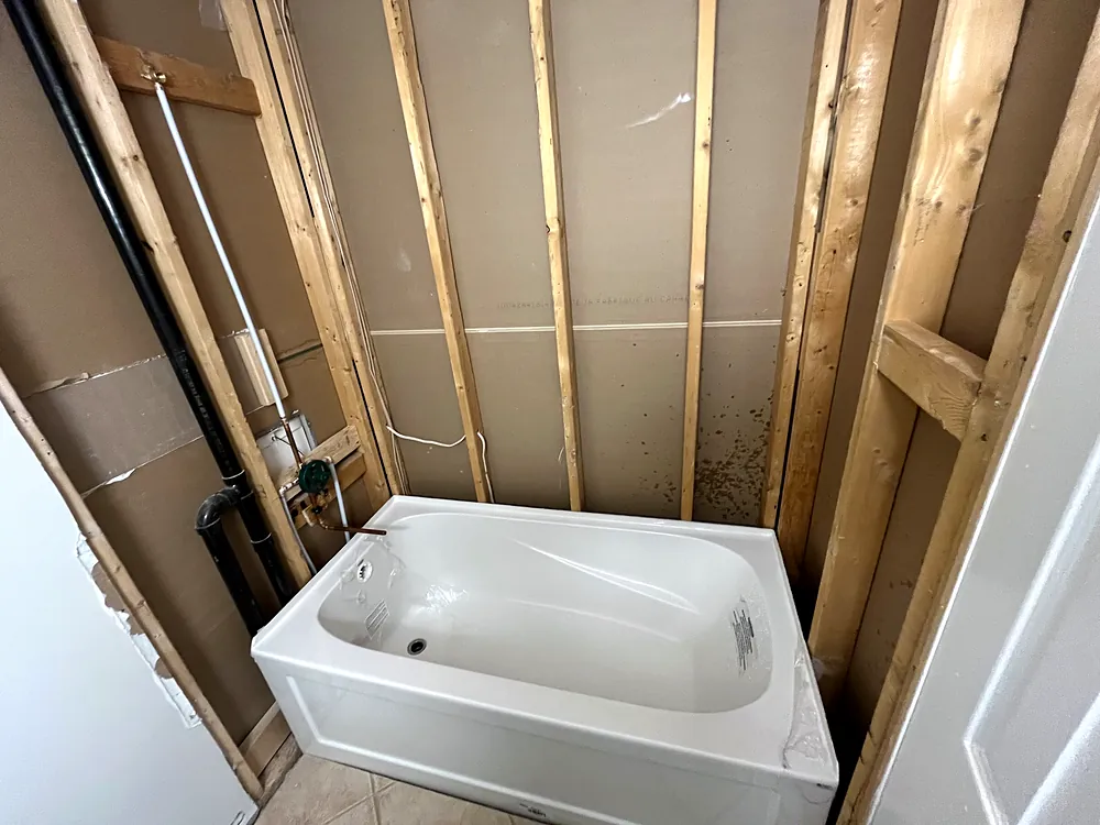 New bathtub set in a framed wall during construction