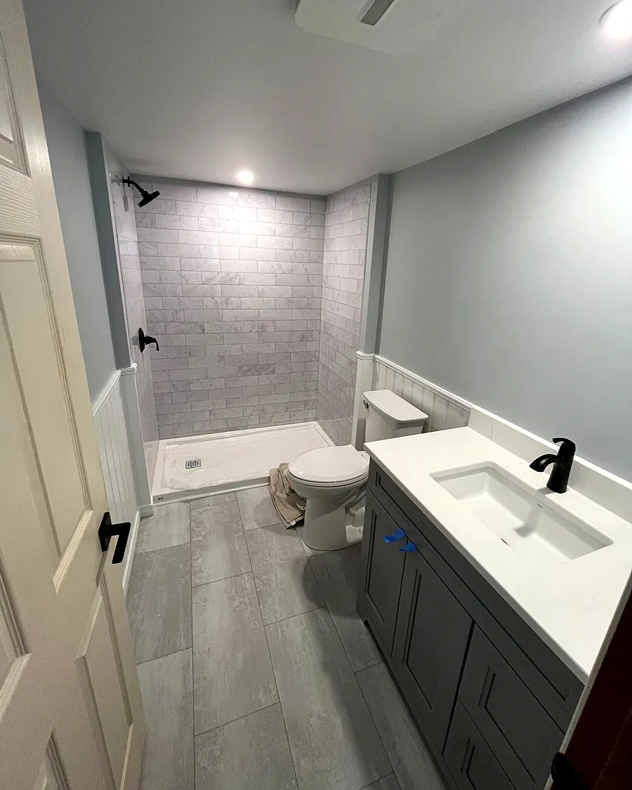 Finished basement bathroom with tiled shower, toilet and vanity